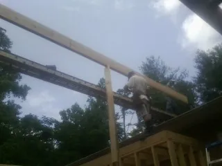 Carpenter setting a ridge beam over a new addition frame — Ice Dam Removal by Roofing Brothers in Argos