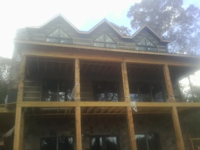 Dormers and porch framing on a large log home under construction — Roof Coating work by our crew in Argos