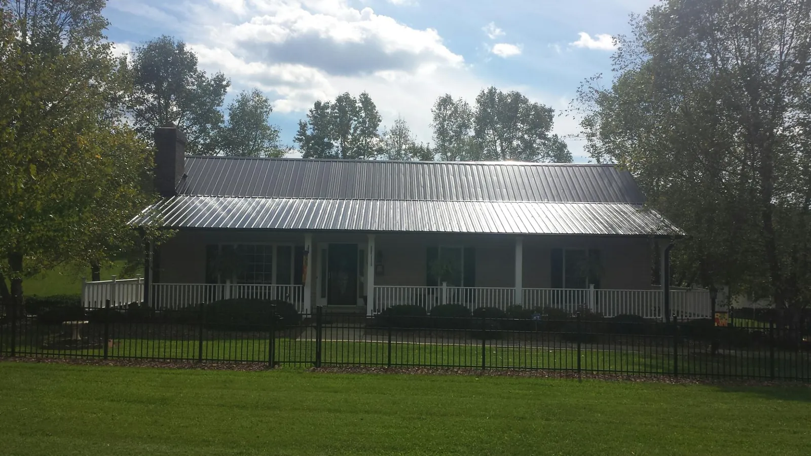 Gray metal roof on a brick ranch with a full width front porch — Gutter Guard Installation work by our crew in Argos