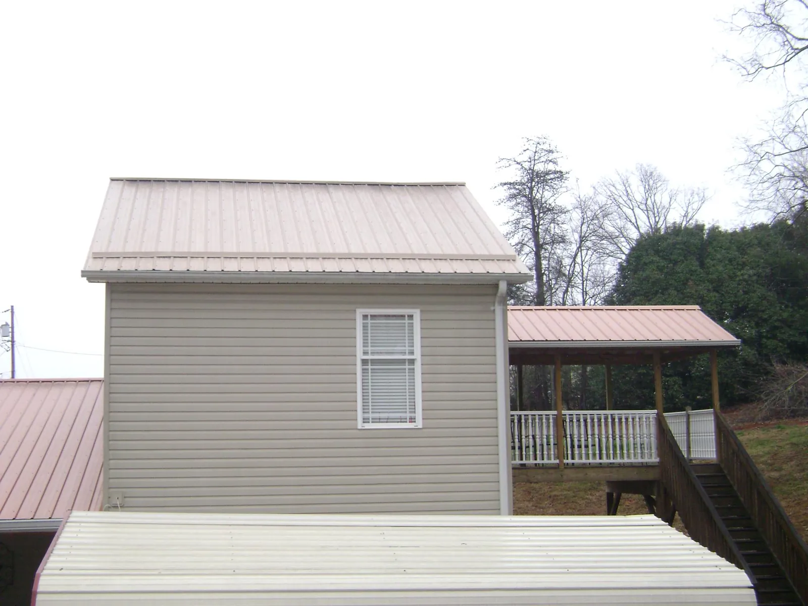 Tan metal roofs on a two story addition and attached porch, from a Roof Replacement job in Argos