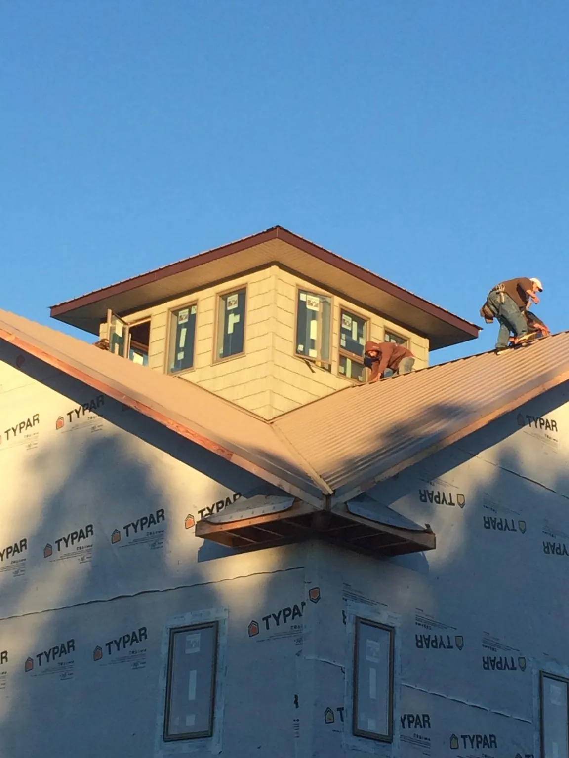 Roofers working around a rooftop cupola on a new metal roof at sunset — Roof Waterproofing in Argos by Roofing Brothers